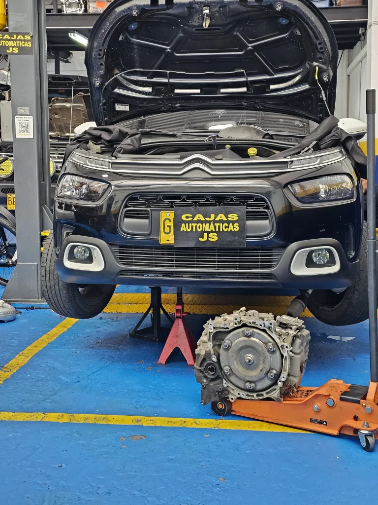 Vehículo Citroën en mantenimiento con la caja automática separada sobre el piso del taller.